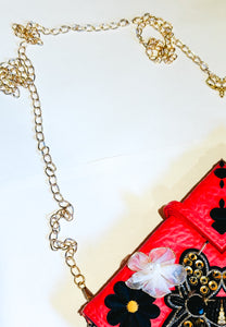 Faux red leather small clutch wallet with bee and flower patches and a gold chain strap.